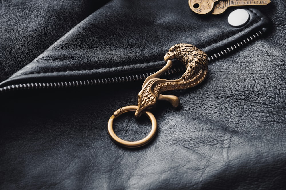 a golden snake keychain on a black leather jacket