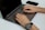 A close-up of hands typing on a keyboard with a smartphone nearby.