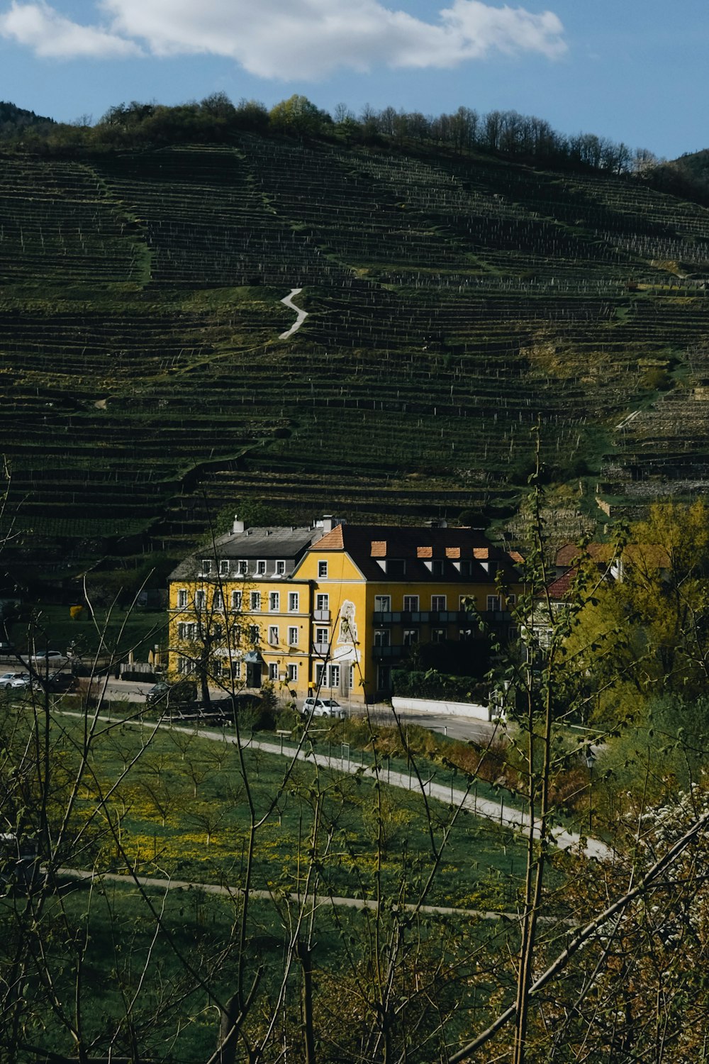 uma grande casa amarela sentada no topo de uma encosta verde exuberante