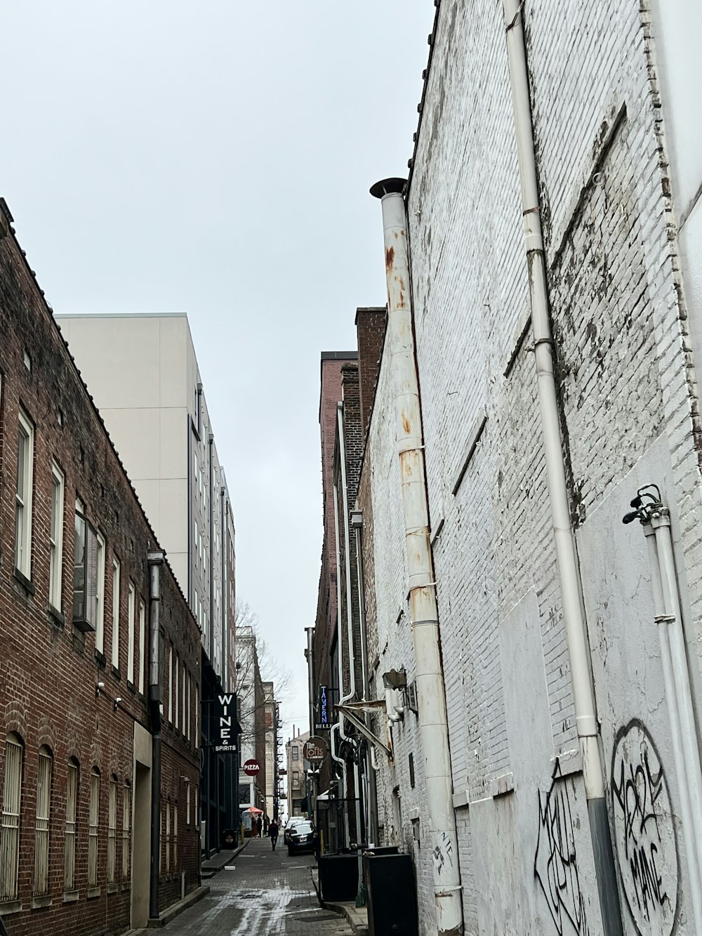 a narrow street with graffiti on the side of buildings