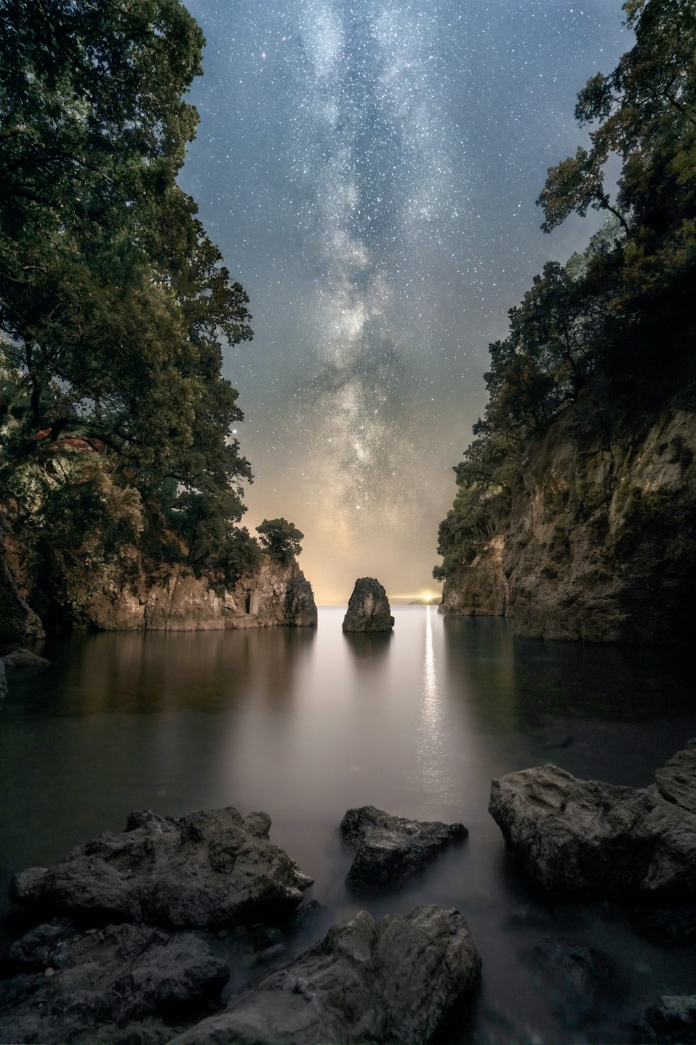 um corpo de água cercado por rochas sob um céu noturno