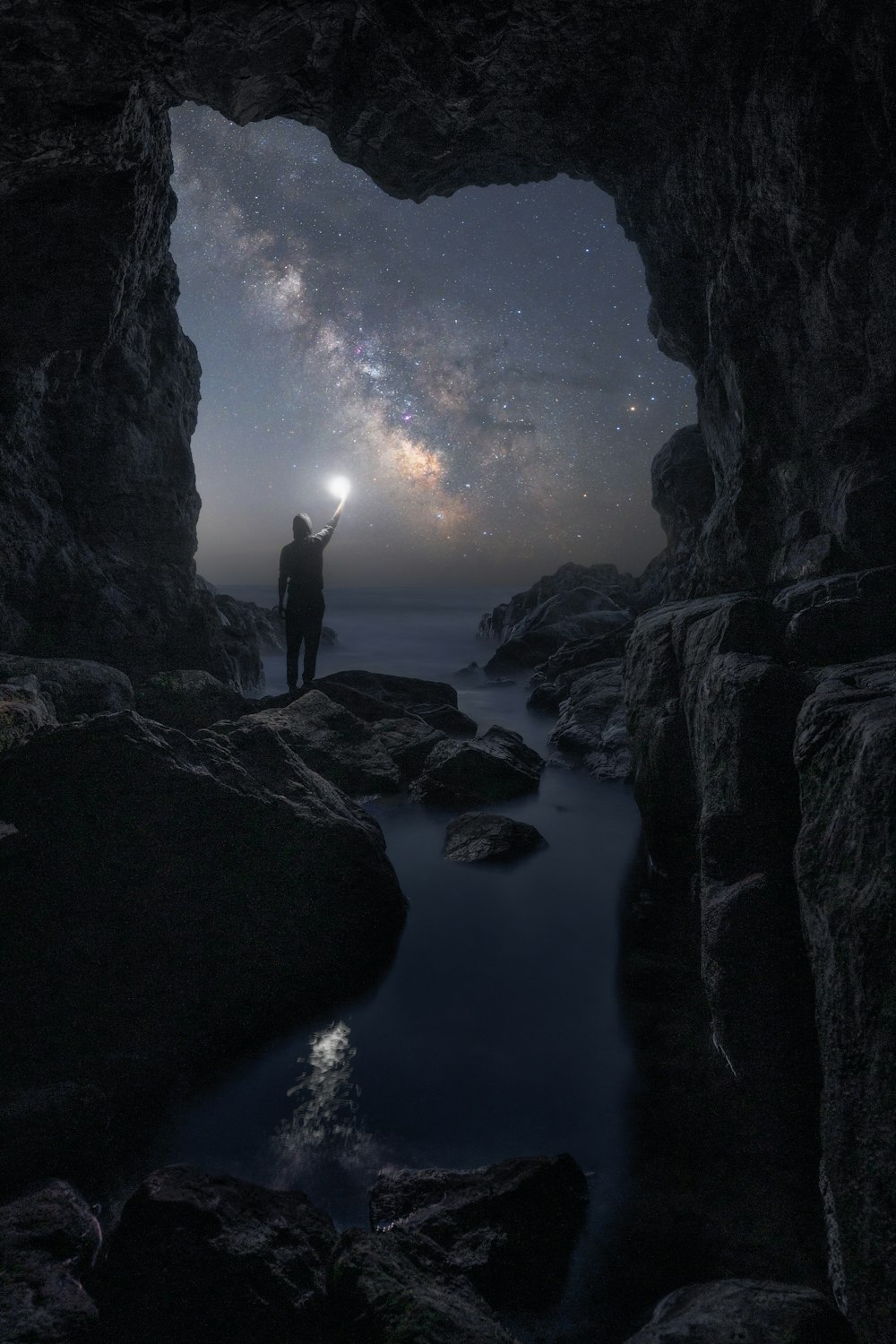 Un uomo in piedi in una grotta che guarda le stelle