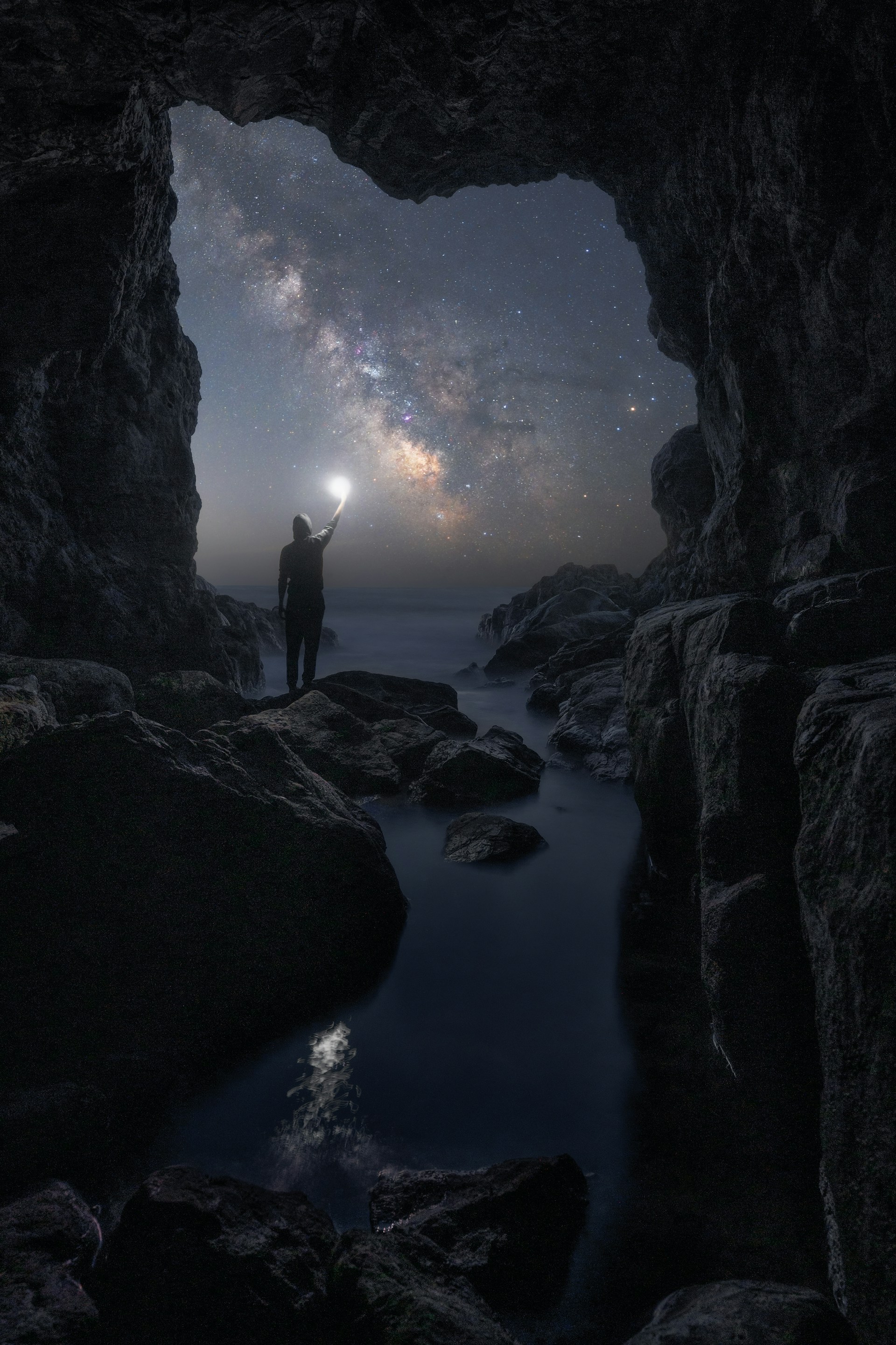 a man standing in a cave looking at the stars