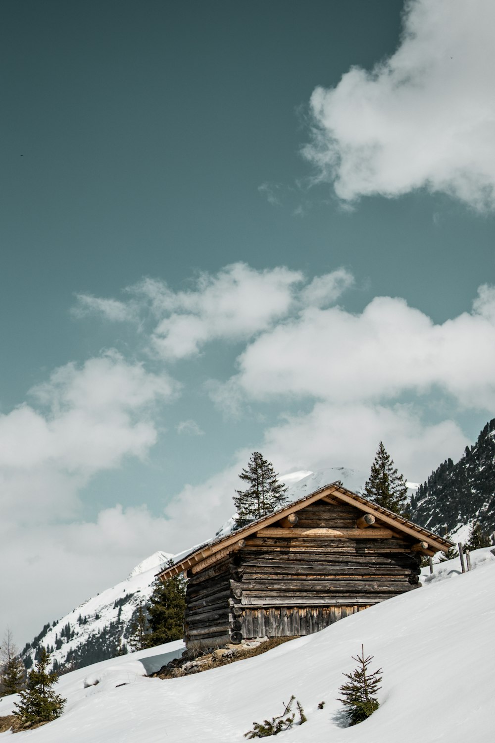 a log cabin on a snowy mountain under a cloudy sky