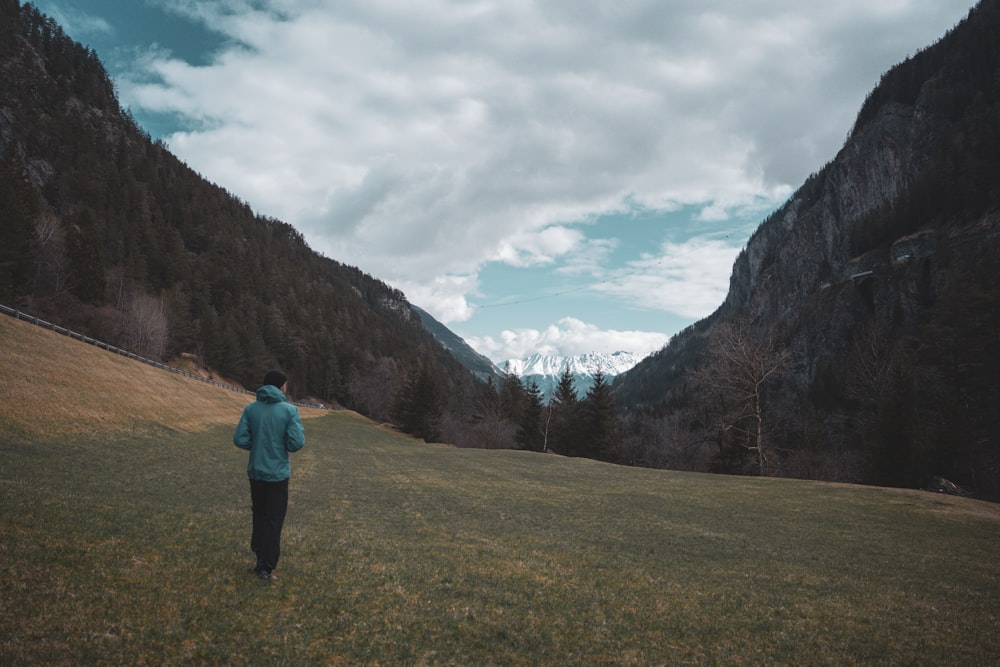 a person standing in a field with mountains in the background