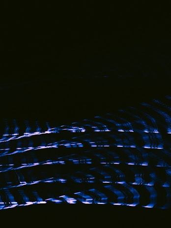 Abstract, minimalistic waveform art rendered in electric blue lines floating on a deep black backdrop.