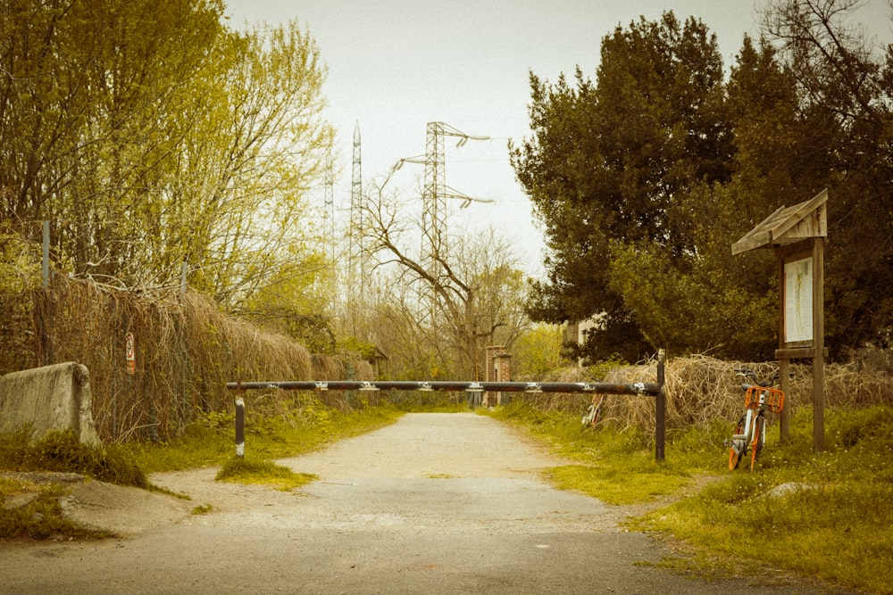 a dirt road with a gate and a bike parked on the side of it