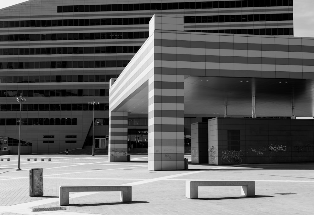 a black and white photo of two benches in front of a building