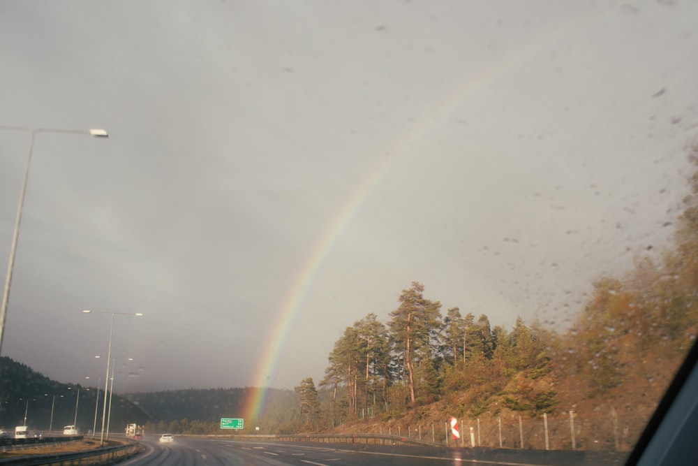 a rainbow is seen in the sky over a highway