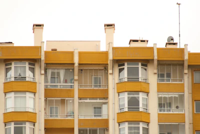 Front view of a bright 2BHK apartment in Viveknagar with bold black window frames and yellow accents.