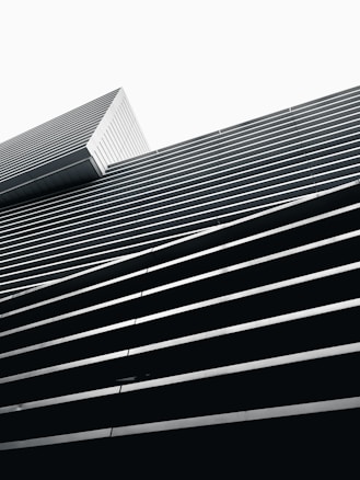 A modern architectural structure featuring a series of horizontal lines and angles, creating a geometric pattern with a minimalist aesthetic.