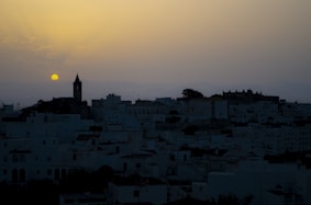 the sun is setting over a city with tall buildings