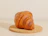 Close-up of a golden, flaky croissant resting on a rustic wooden table with soft morning light.