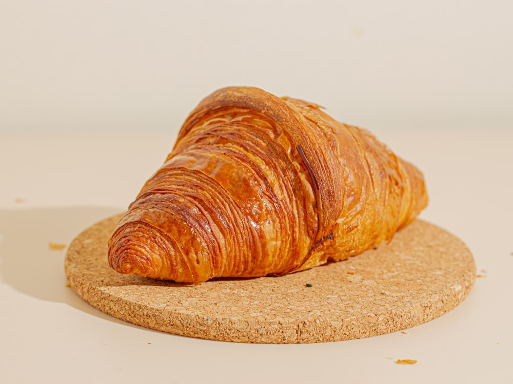 a croissant sitting on top of a cork coaster
