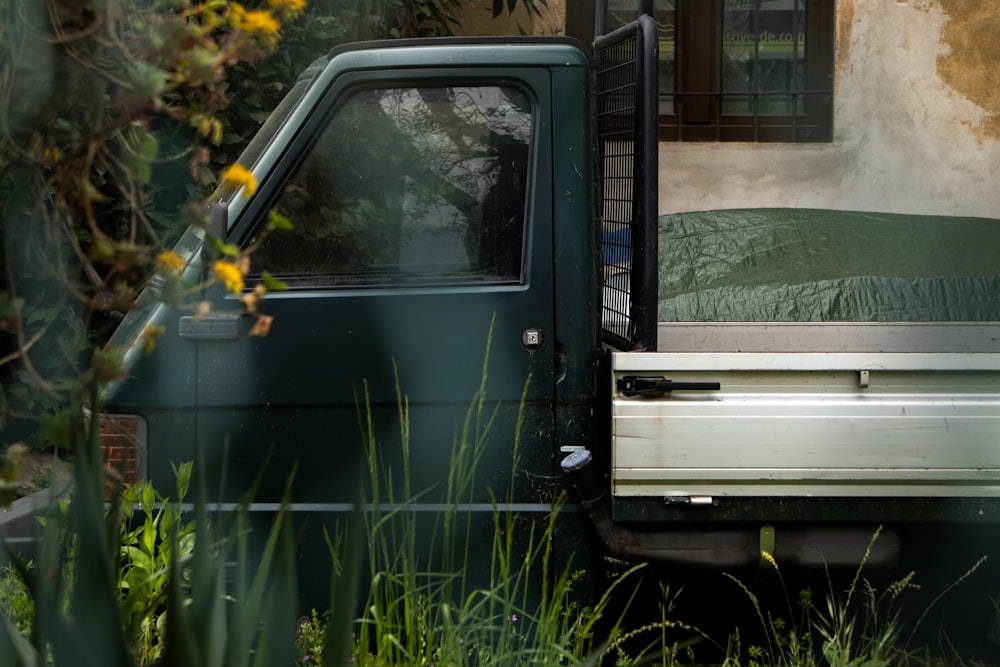 a green truck parked next to a building