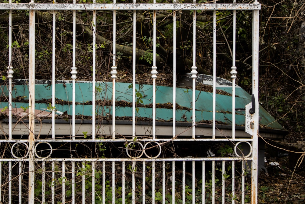 a rusted out boat sitting in a fenced in area