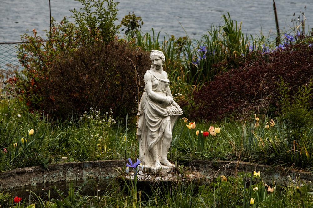 a statue of a man in a garden by a body of water