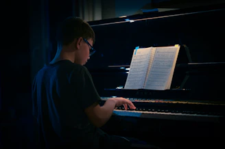 a young man sitting at a piano in the dark