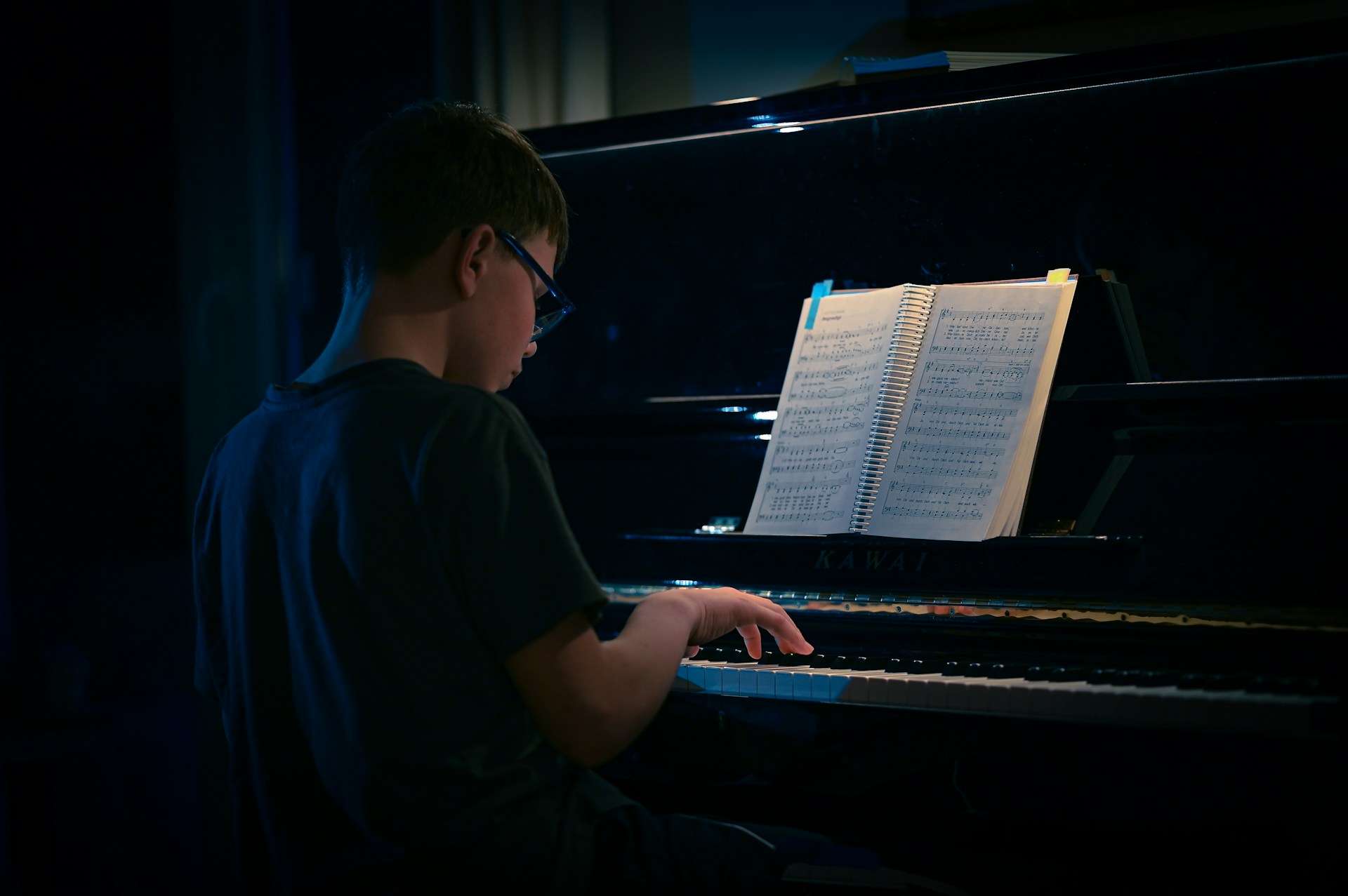 a young man sitting at a piano in the dark
