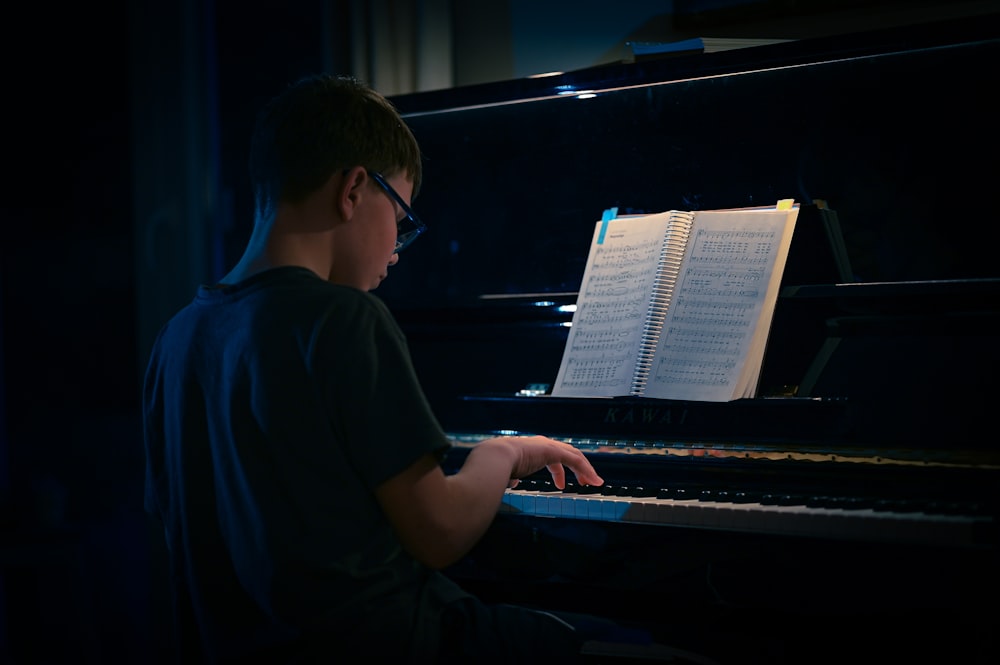 a young man sitting at a piano in the dark