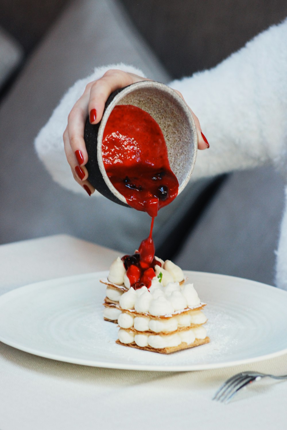 a person pouring sauce onto a dessert on a plate
