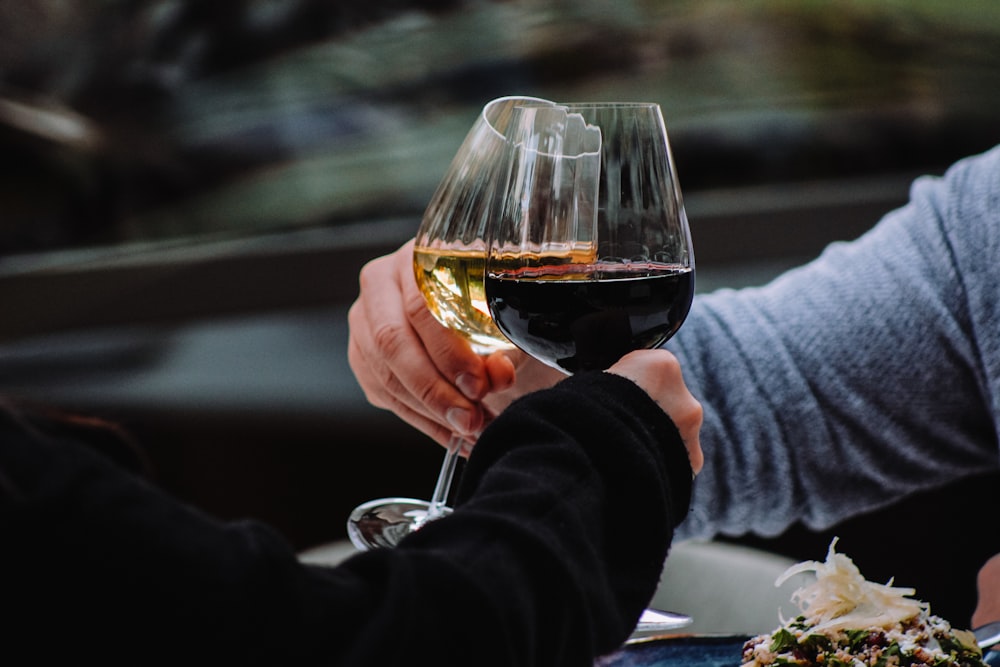 a couple of people holding hands over a glass of wine