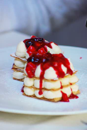 A beautifully plated mille-feuille with fresh berries and a drizzle of caramel sauce.