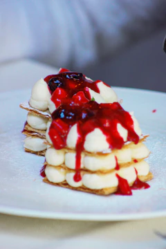 A beautifully plated mille-feuille with fresh berries and a drizzle of caramel sauce.