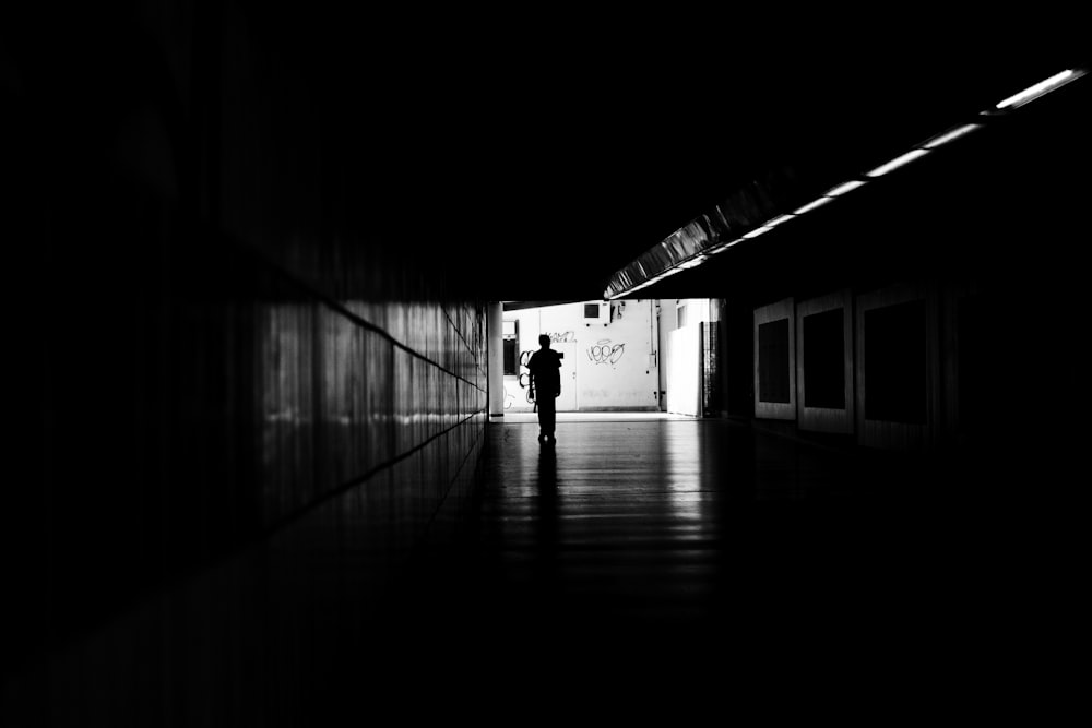 a black and white photo of a person standing in a dark hallway