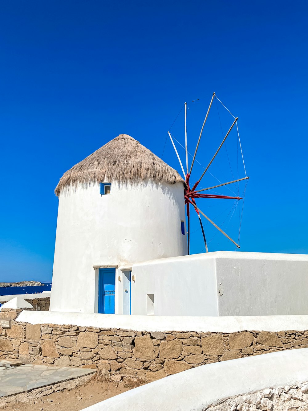 a white building with a thatched roof and a blue door