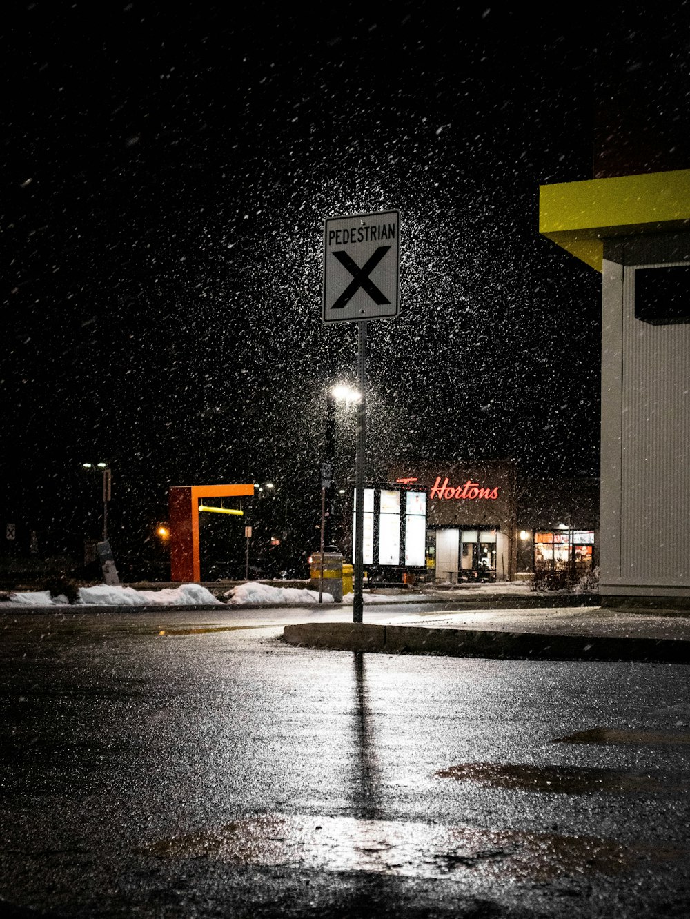 a crosswalk sign in the snow at night