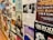A wall covered with various posters and flyers for music events and performances. Most of the posters feature bands, details of concert dates and locations, and artistic designs. The wall has a collage effect with overlapping elements creating a busy and colorful atmosphere.