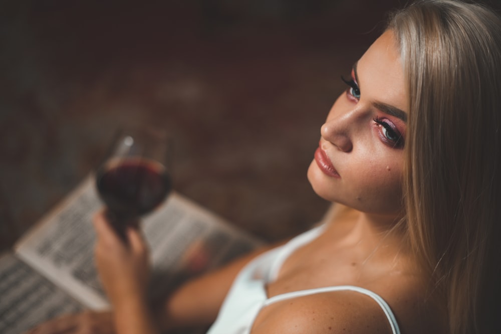 a woman holding a glass of wine and reading a book