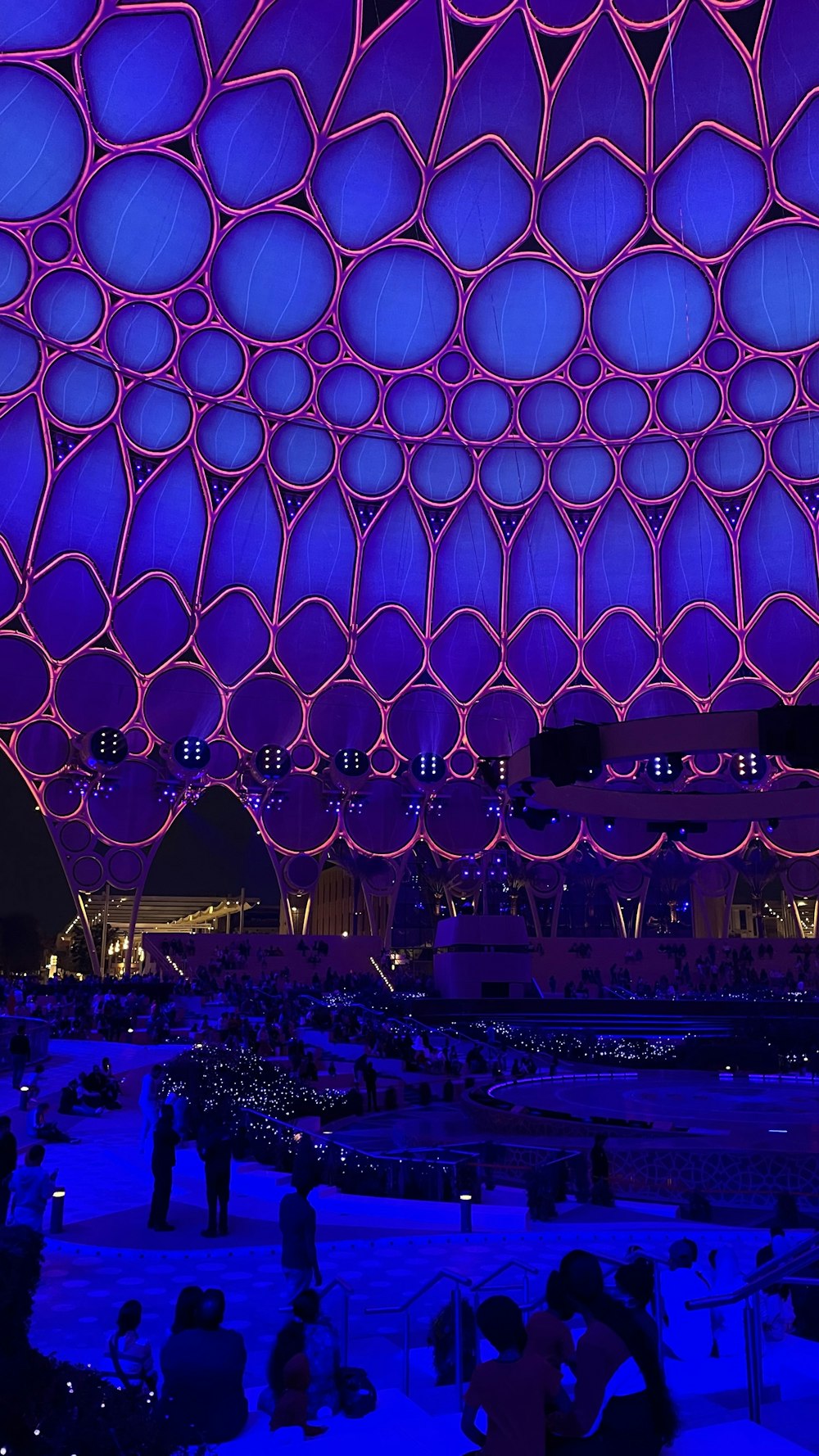 a group of people standing around a building under a purple sky