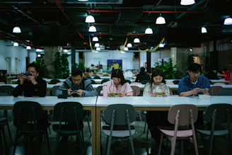 A diverse group of young people engaging with digital devices in a cozy, modern setting.