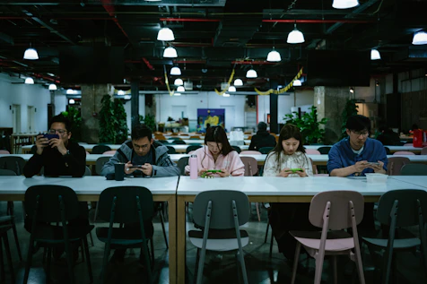 A group of Gen Z students studying together with laptops and smartphones in a cozy campus cafe.