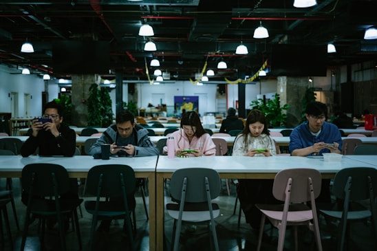 A diverse group of people examining smartphones in a bright, modern office setting.