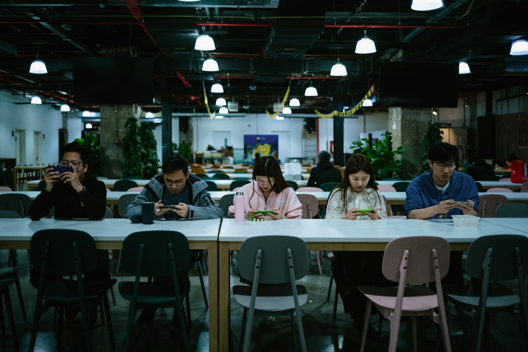 a group of people sitting at a table with cell phones,
