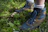 Close-up of a person applying tick repellent on hiking boots.
