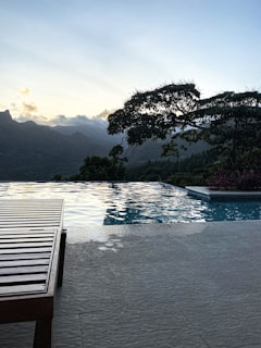 a wooden bench sitting next to a swimming pool