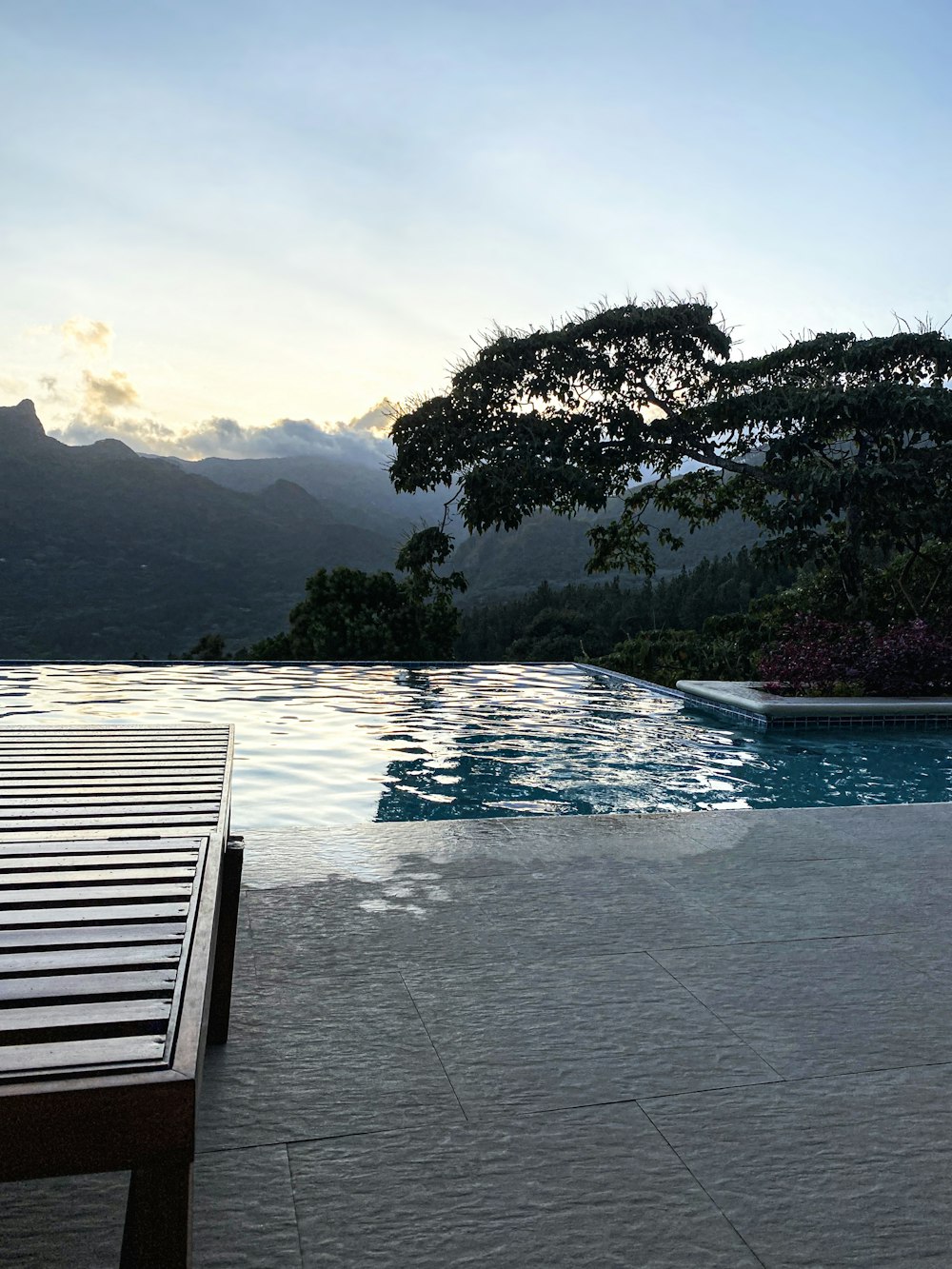 a wooden bench sitting next to a swimming pool