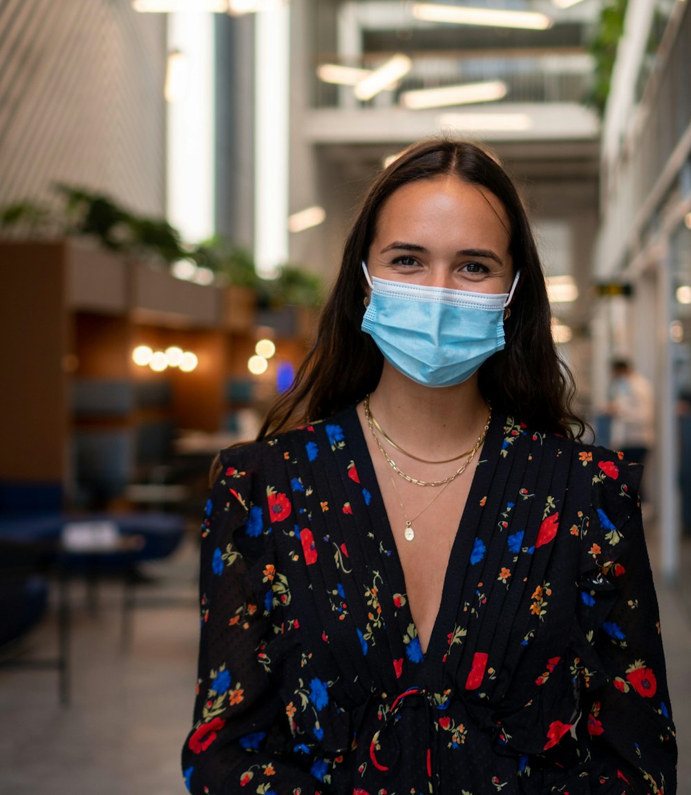 a woman wearing a face mask standing in a hallway