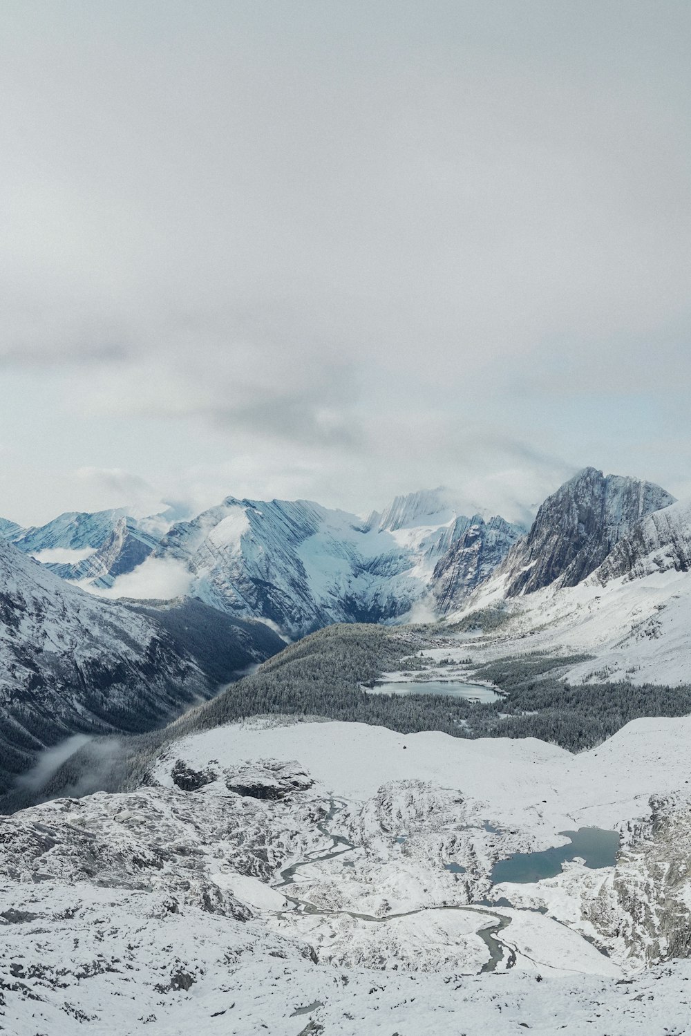 a snowy mountain range with a lake in the foreground