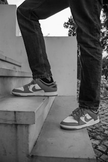 Dynamic image of a model walking in black and white sneakers on urban stairs.