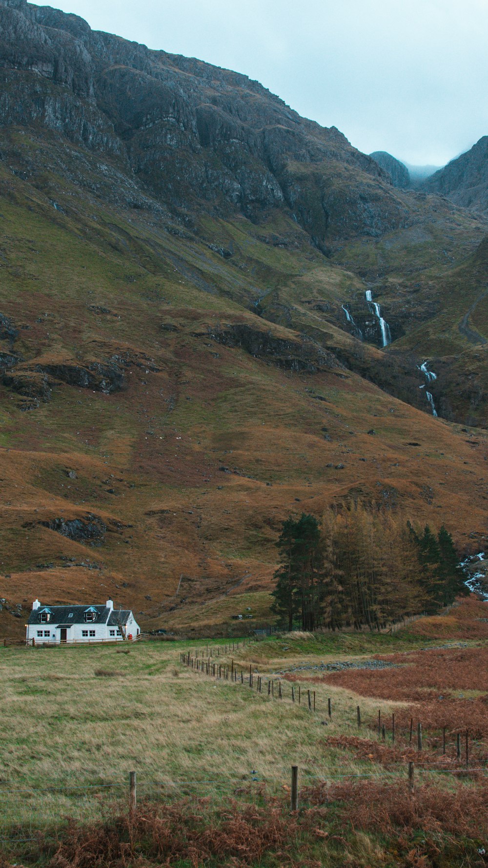 a house in the middle of a field with mountains in the background