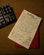 a piece of paper with writing on it next to a keyboard