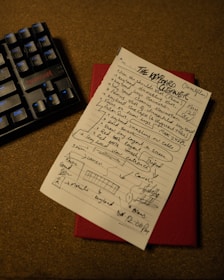 a piece of paper with writing on it next to a keyboard