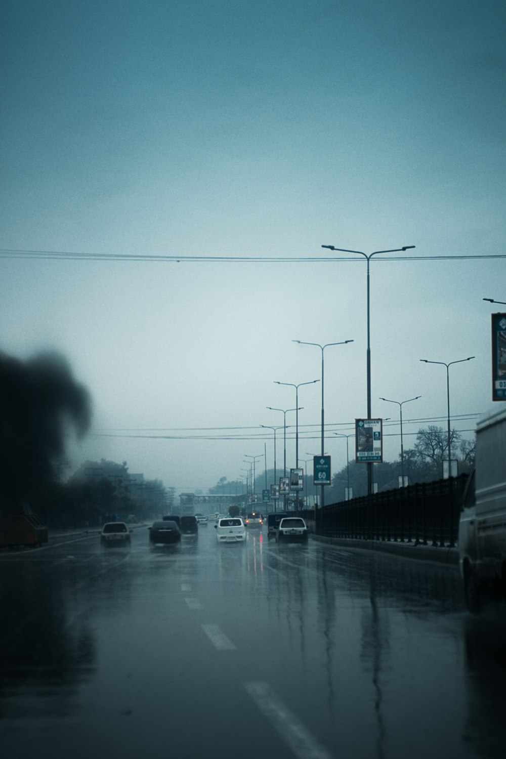 cars driving down a wet road in the rain