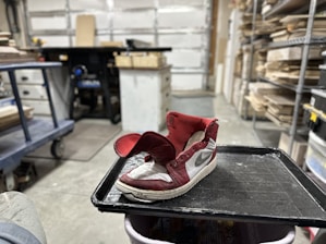 Close-up of hands crafting athletic shoes in a workshop environment.