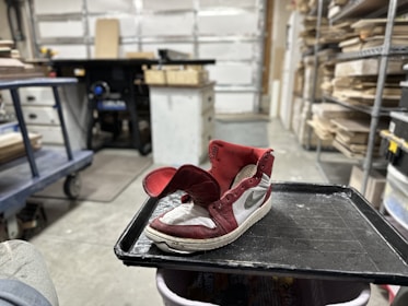 Close-up of hands crafting athletic shoes in a workshop environment.